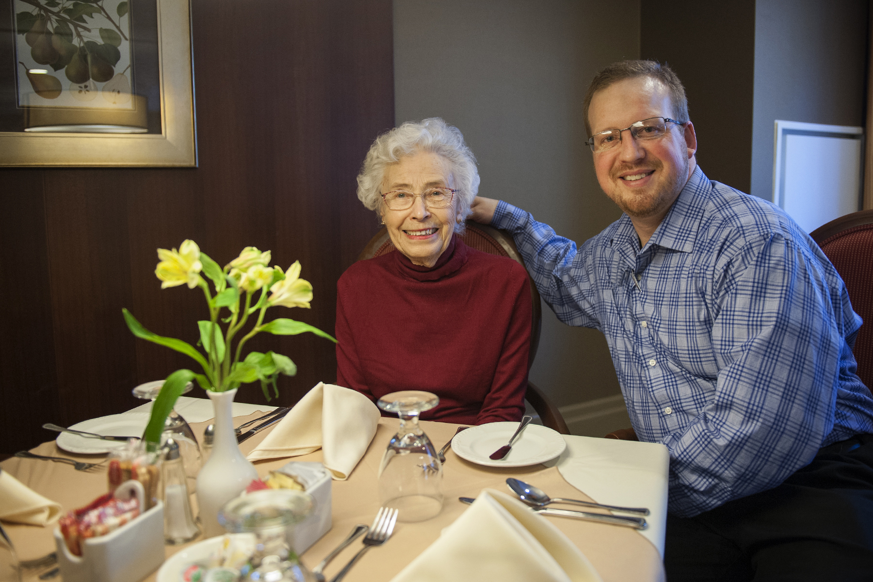 Hospitality worker and resident of a retirement home seated at a dining table